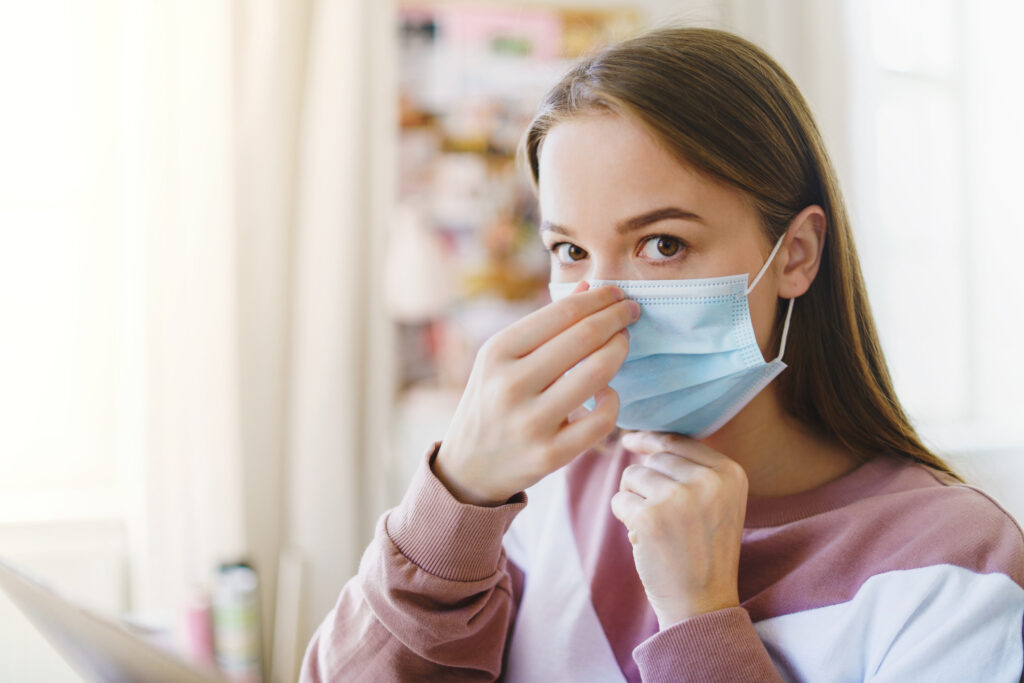 Young female student with face mask indoors, looking at camera.