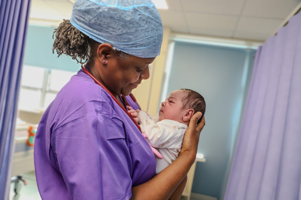 A midwife holds a newborn baby in her arms