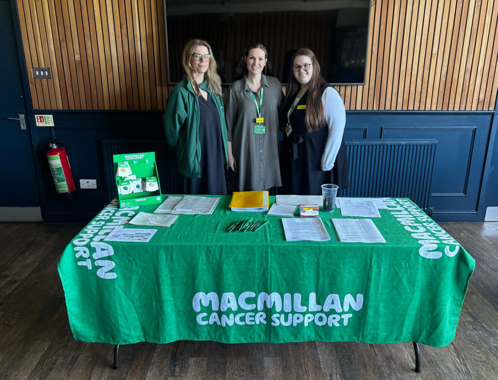 Some of the Macmillan Cancer Support Group team standing behind an awareness display