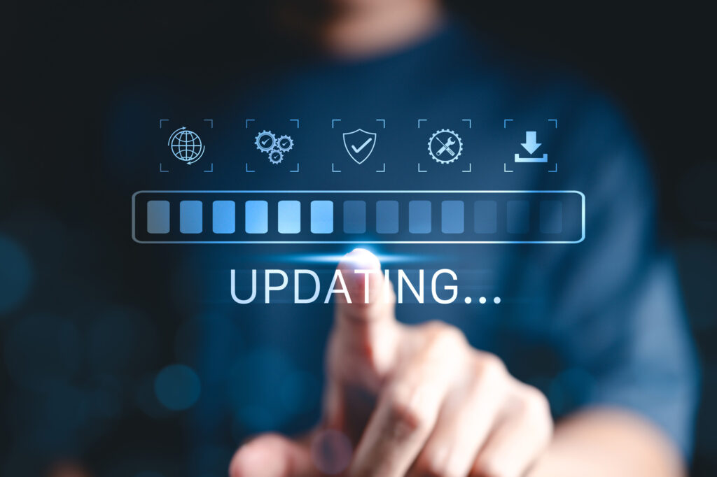 A loading bar that has the word UPDATING underneath. A blurred hand touches the screen. Image represents a computer update taking place.