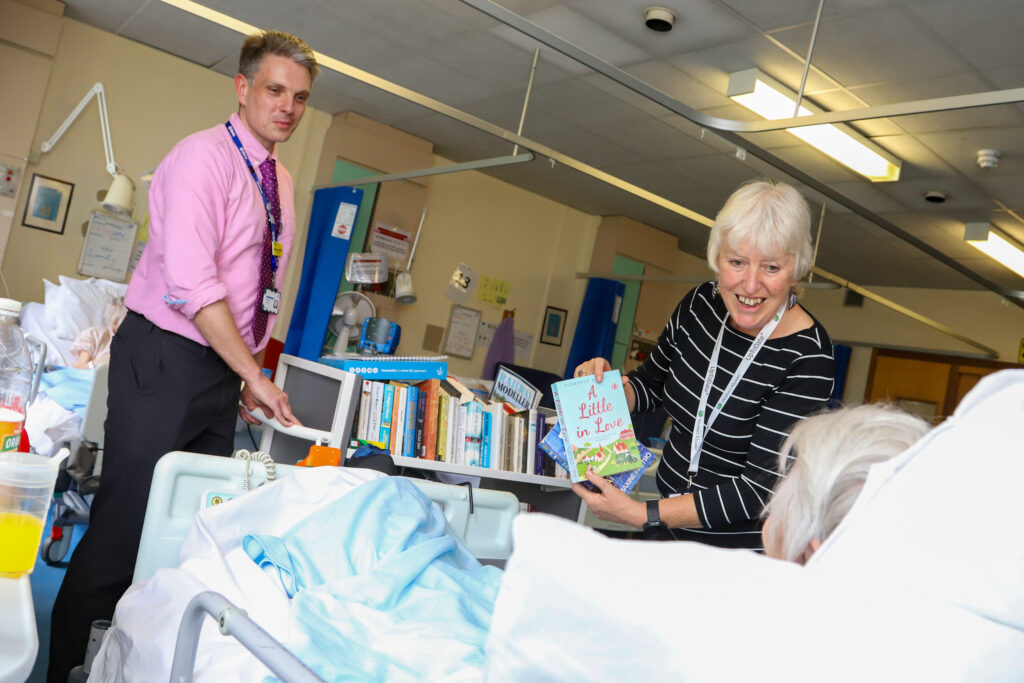Volunteer showing books to a patient